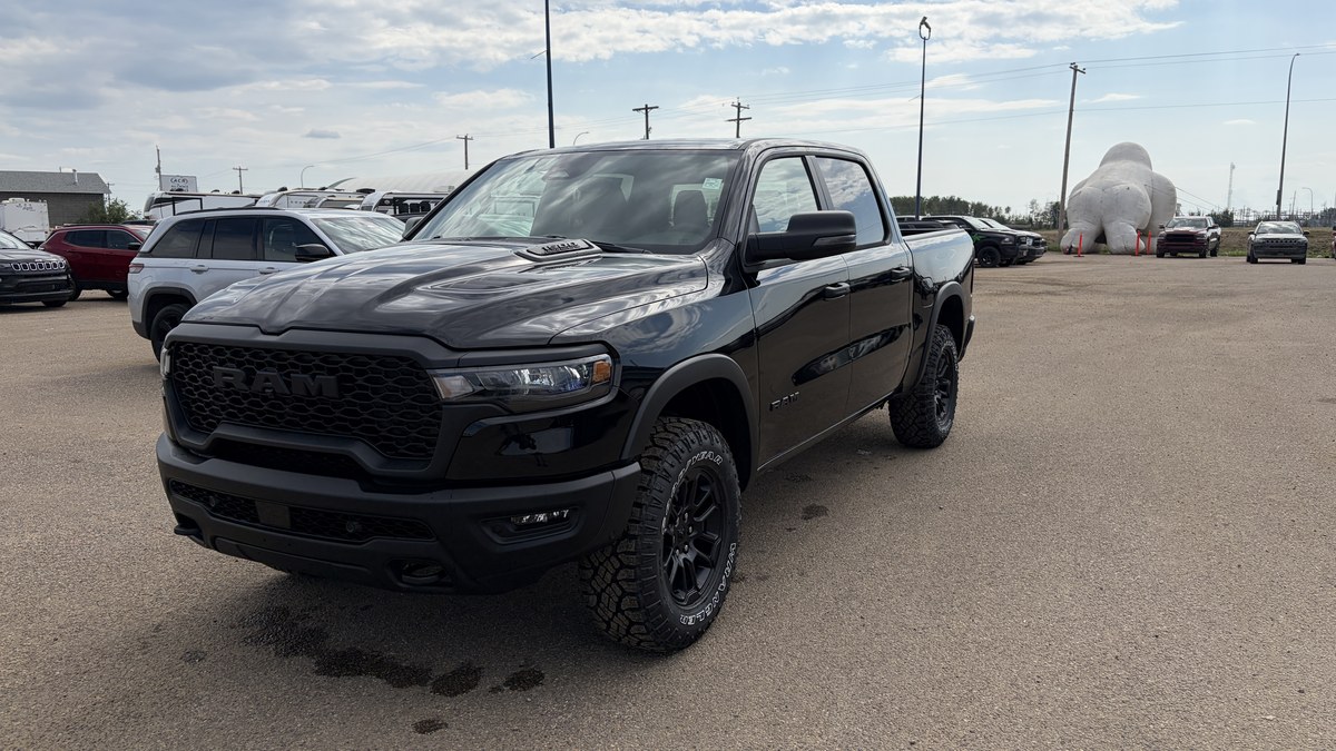 Black Ram 1500 pickup parked on a gravel dealership lot